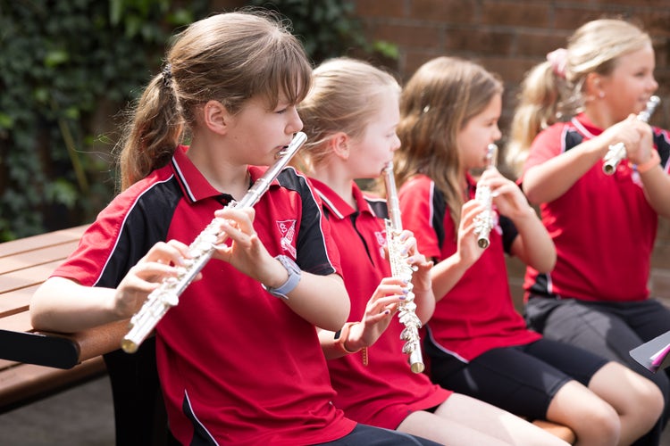 Four girls are outside playing flutes.